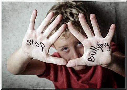 prevent bullying: boy holds up his hands that say "stop bullying"
