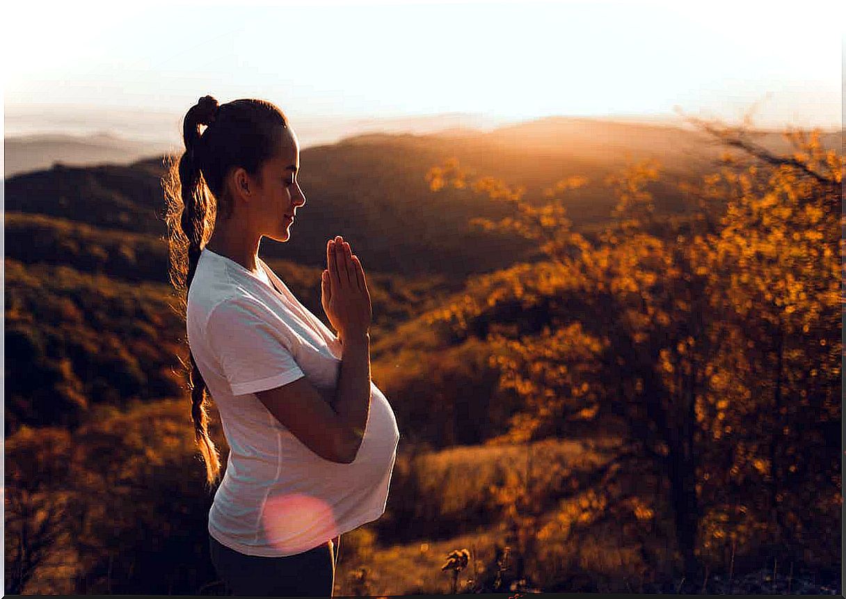 A pregnant woman meditating in nature.