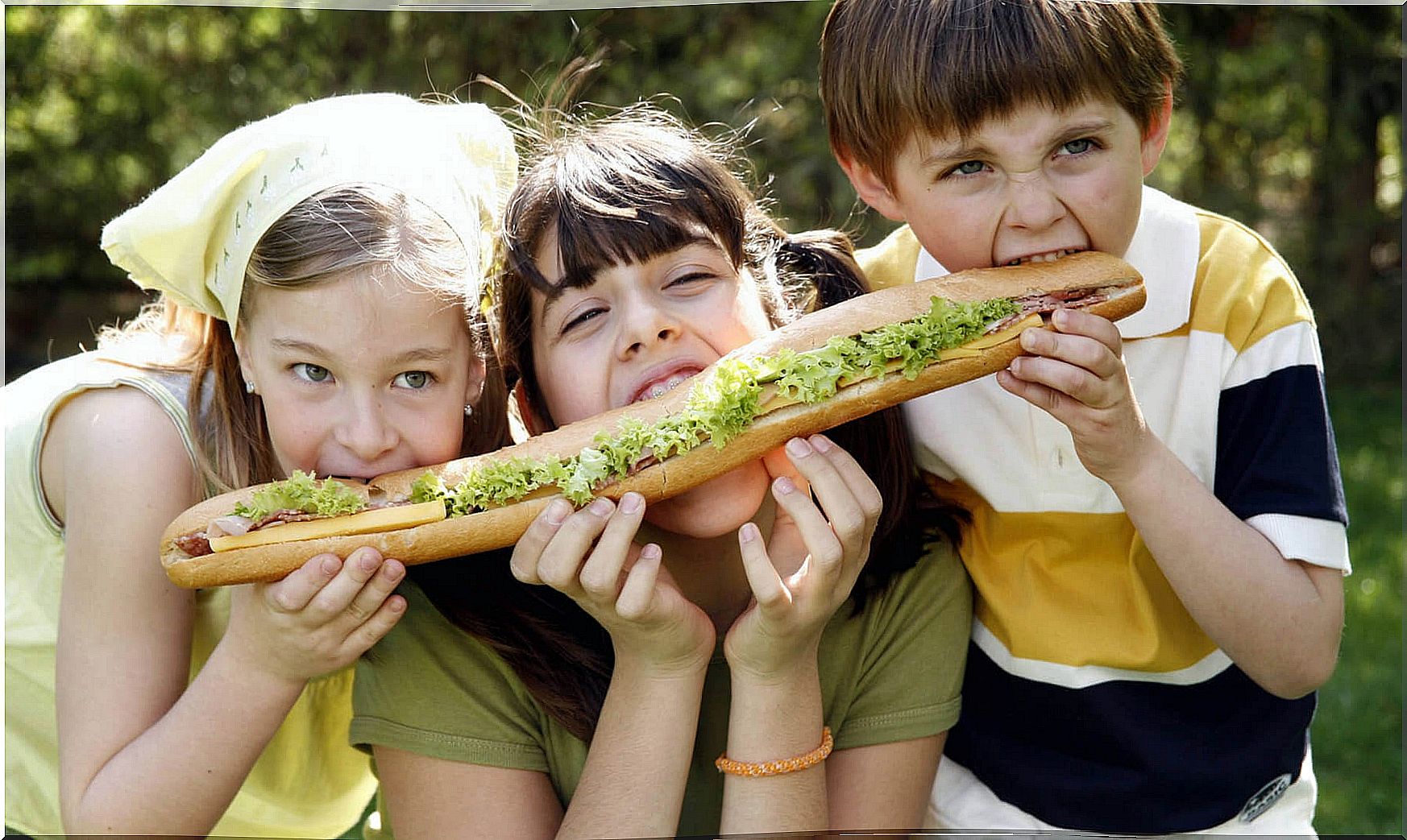 Three children share a sandwich