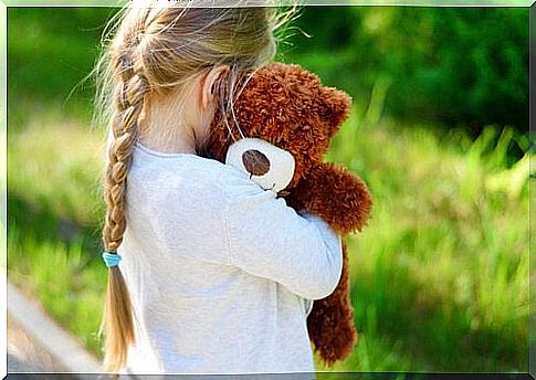 A girl hugs a teddy bear.