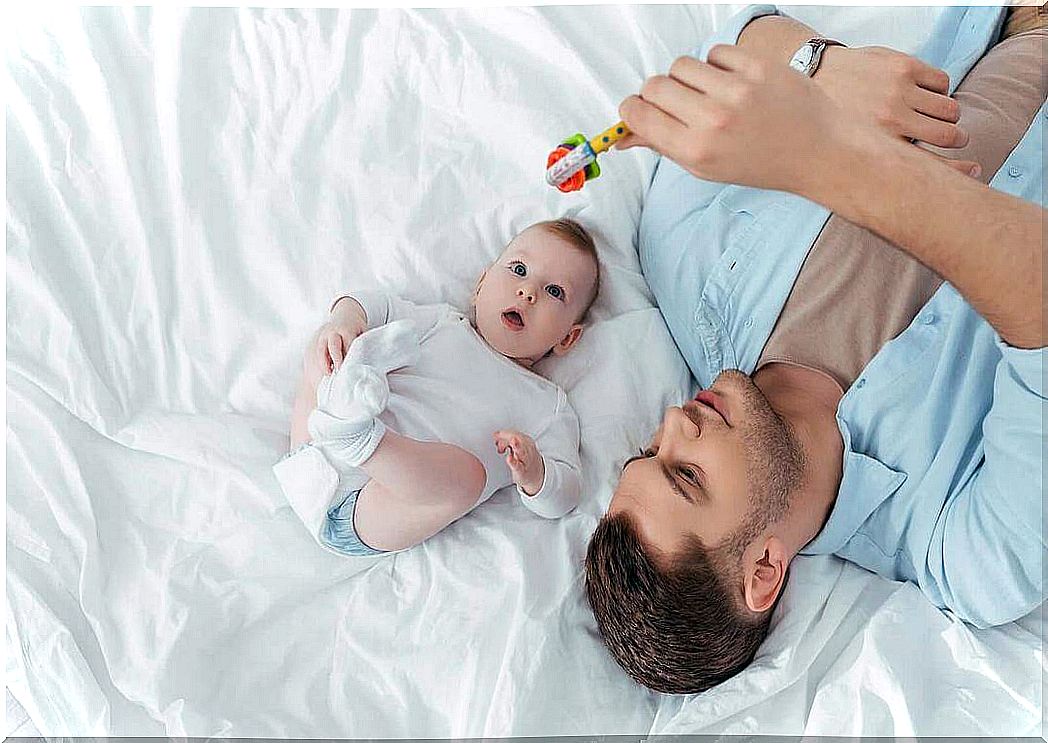 create a bond with your baby: dad plays with rattle with baby