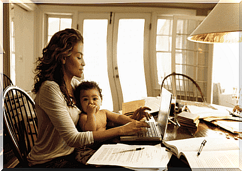 mothers working from home: mother at computer with baby in her arms