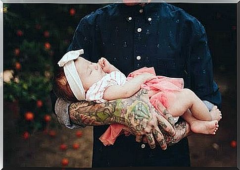 Man with tattooed arms holding babies in his arms