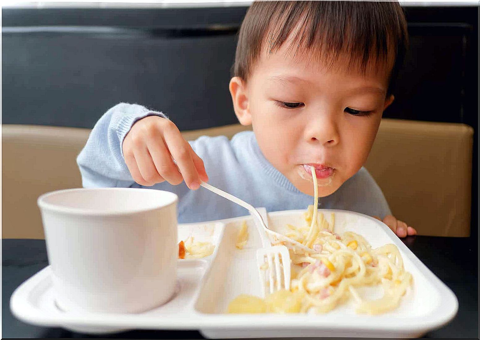 A toddler eating pasta.