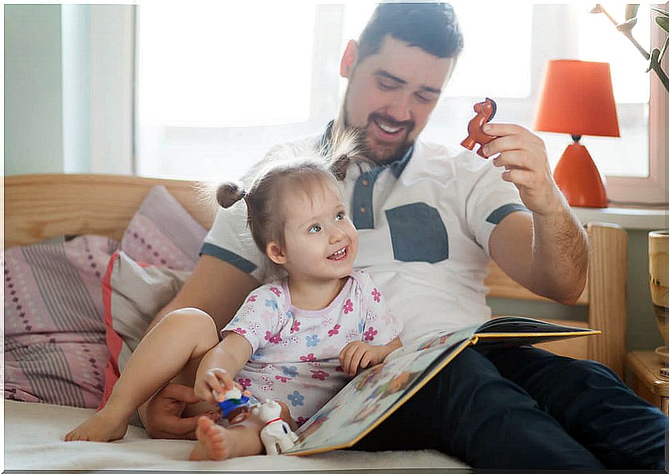 dad looks in book and plays with daughter