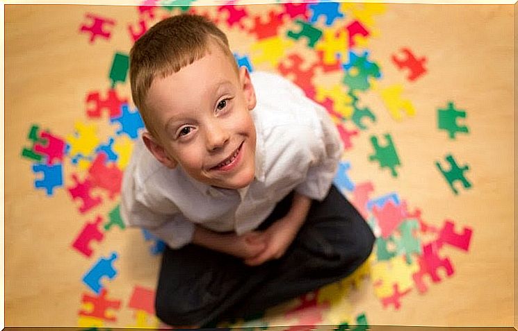 boy sitting among puzzle pieces and looking up at the camera