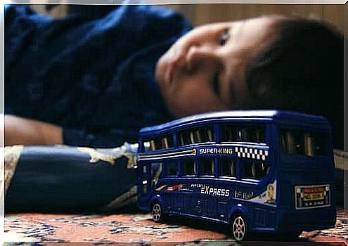 A child with emotional problems is lying next to his toy car.