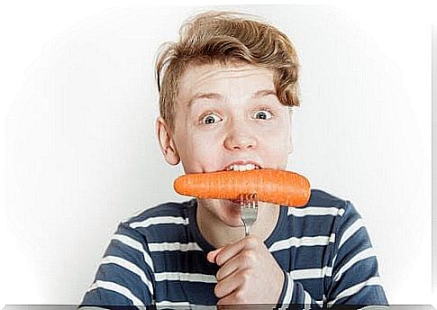 Boy eats carrot on fork