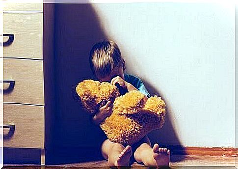 domestic violence: boy with teddy bear sitting in a corner