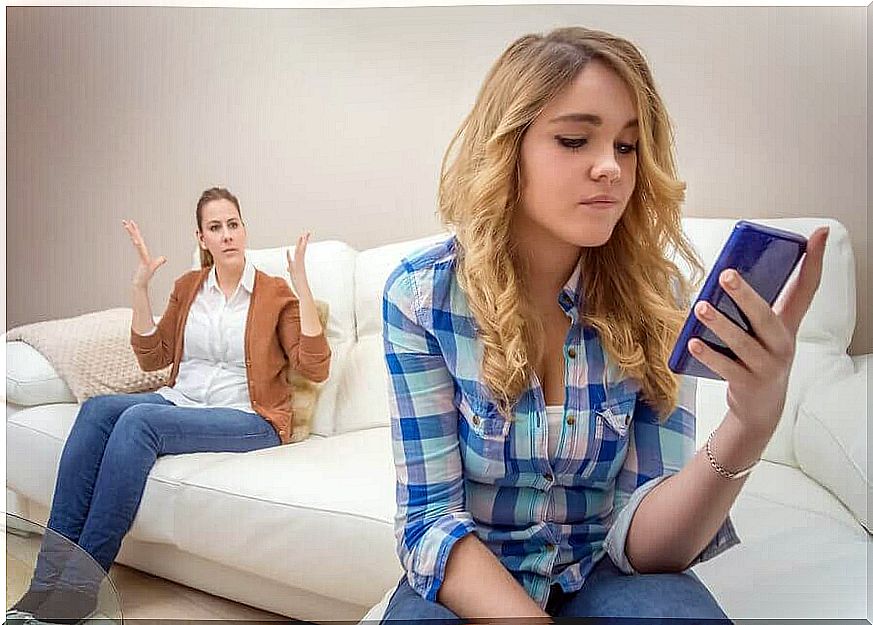 upset mother in the background with teenager with phone in the foreground