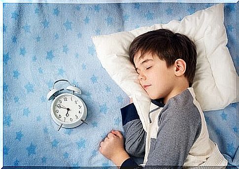 boy sleeping next to alarm clock