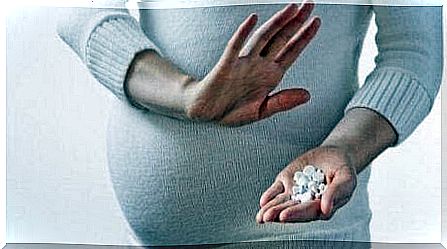 pregnant woman holding up a dismissive hand against pills