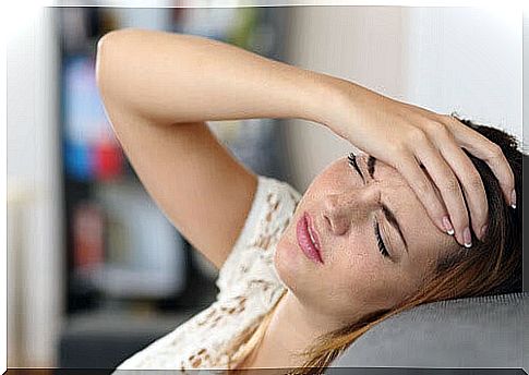migraine during adolescence: girl holds her forehead