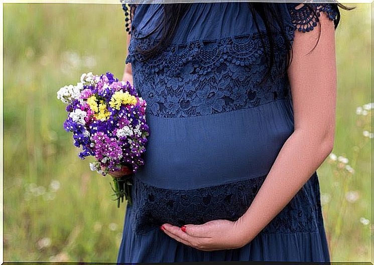 Pregnant woman in blue dress with flower bouquet