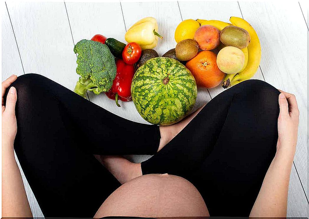 Vitamin K during pregnancy: pregnant woman sits at fruit and vegetables