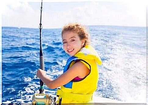 sailing with children: girl with fishing rod on boat