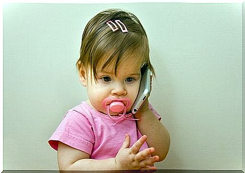 A small child plays that she talks on the phone.