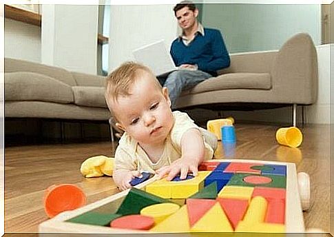 baby playing with blocks, dad in the background